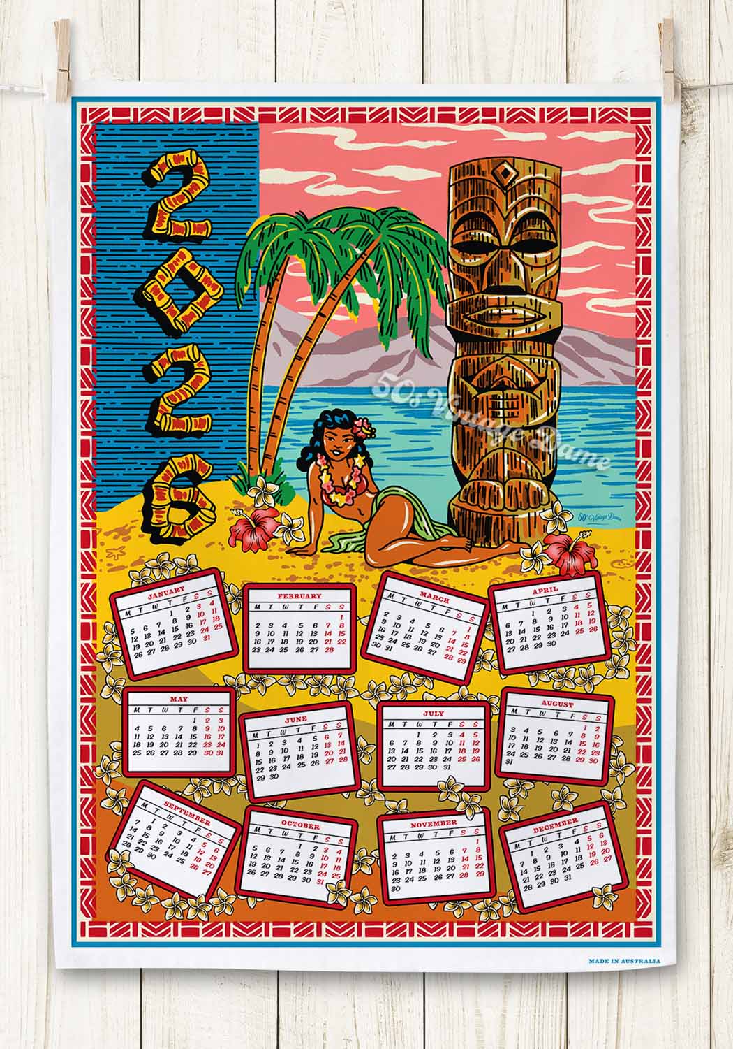 2026 Tiki calendar Teatowel with tropical design featuring a hula dancer and tiki statue on a wooden background.