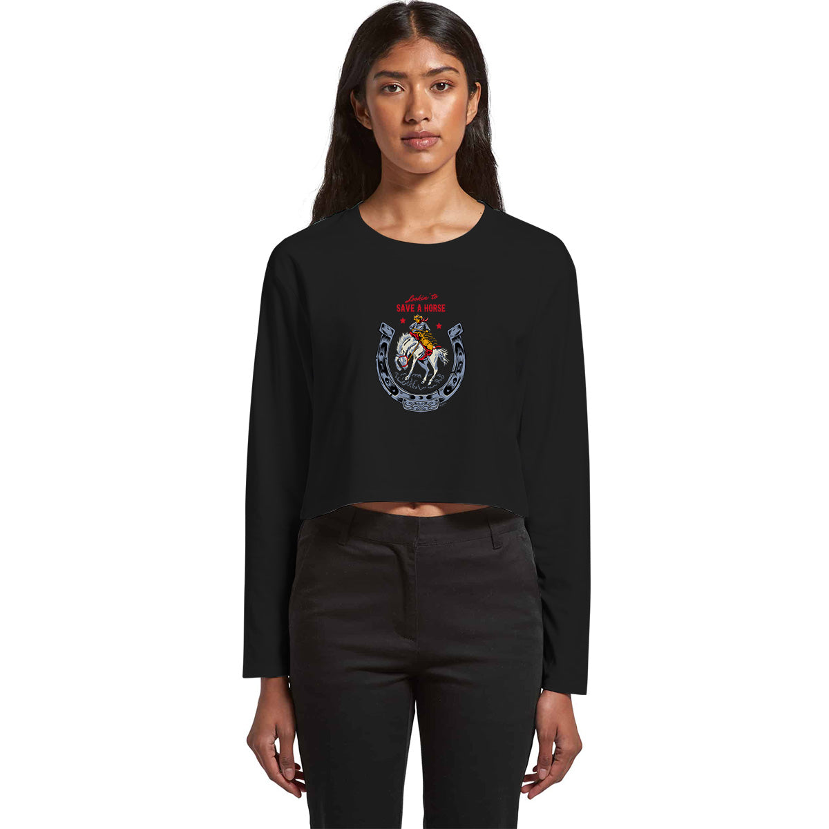 Ladies long sleeved crop t-shirt in black cotton. Front graphic features a vintage-style illustrtion of a cowboy riding a bucking bronco. Text says Lookin' to save a Horse.