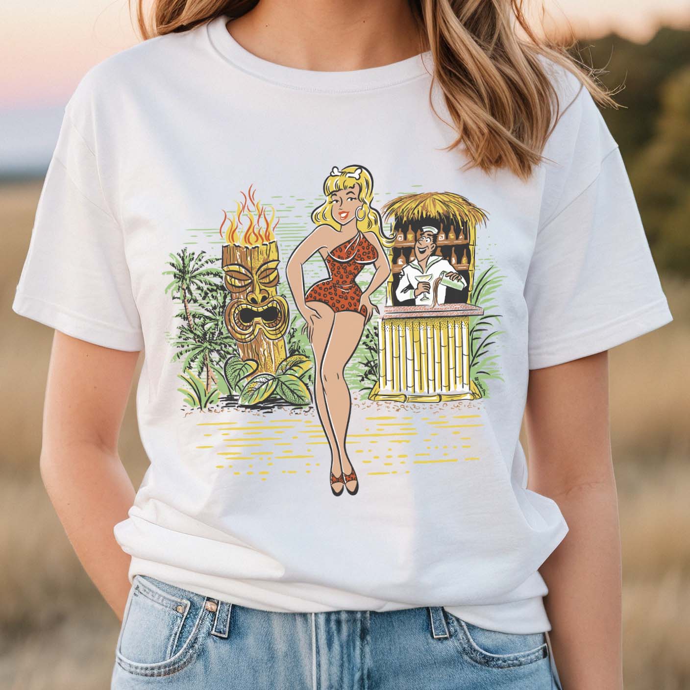 White cotton tee shirt with an original illustration featuring a sexy tiki queen pionup lady. Behind her a tiki statue bursts into flames and a sailor behind a little tiki bar spills his drink because he can't take his eyes off her.