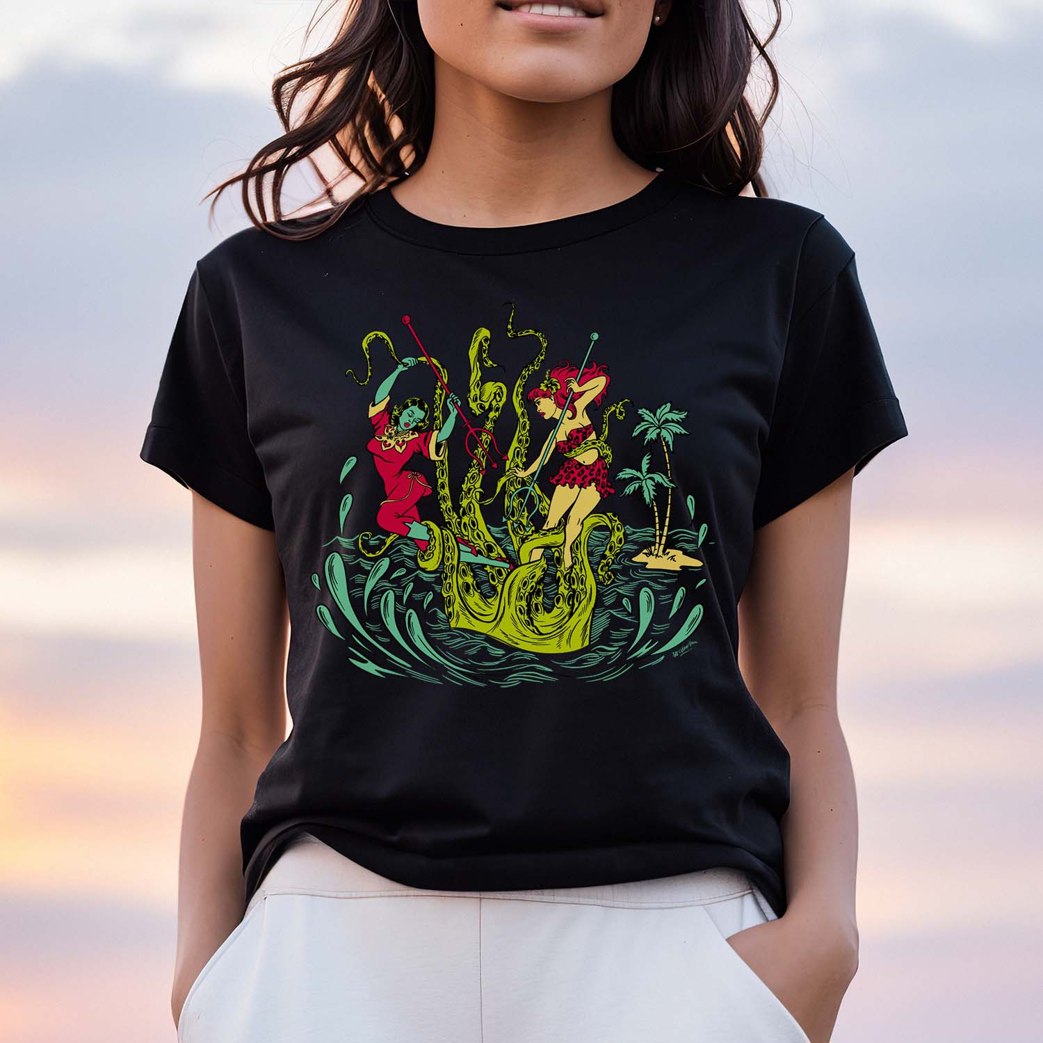 Unisex black tee shirt with a graphic of two women battling a giant Kracken. Shirt is modelled by a woman