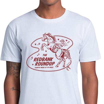 White unisex t-shirt with a cowboy riding a bucking bronco. Text says "The Red Bank Roundup - country music at its finest" A lasso, stars and music notes surround the design.