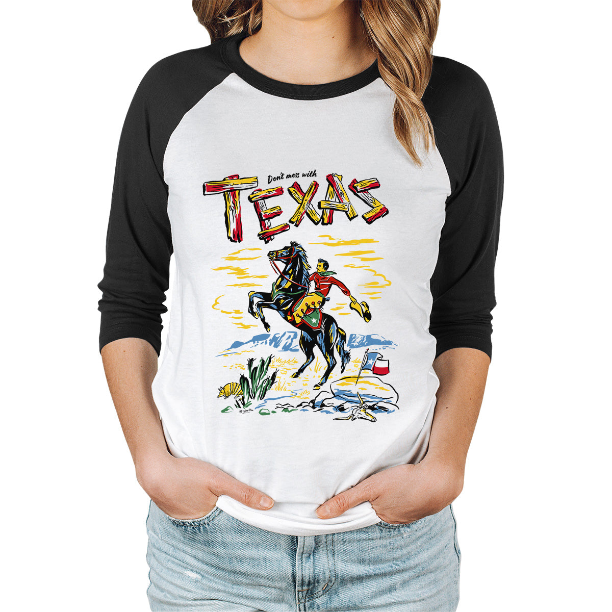 Raglan sleeve t-shirt. Black sleeves and white body. Front image is a vintage style illustration of a cowboy on horseback. Slogan says Don't Mess with Texas. Lady modelling the shirt.