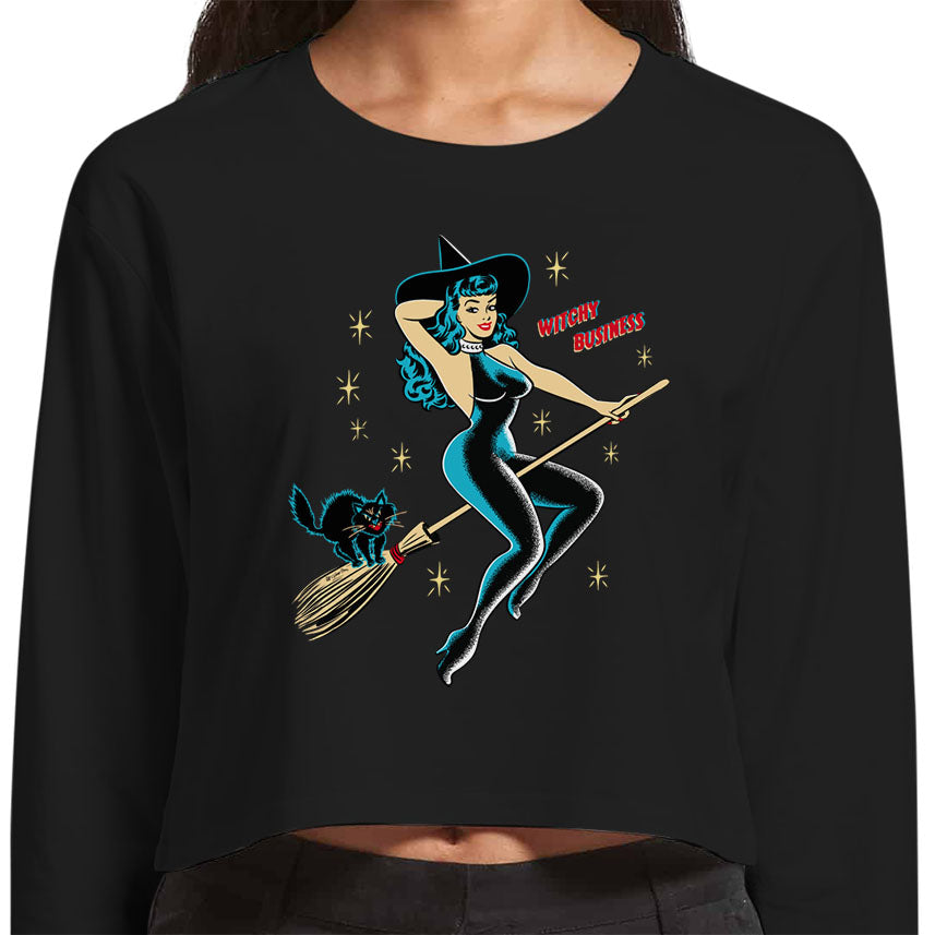 Detail picture of the design appearing on the tee shirt. A vintage pinup witch dressed in a black catsuit is riding a broomstick with a black cat on the back. The text reads "Witchy Business"